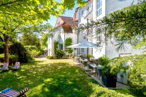 Großer Hotelgarten mit Terrasse und Liegeweise